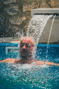 Man by fountain swimming in pool