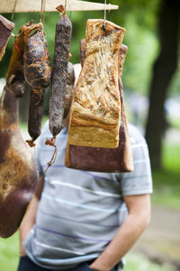 Close-up of smoked bacon hanging with man in background