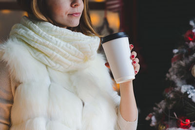 Midsection of woman having coffee during christmas