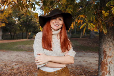 Portrait of smiling young woman standing against trees