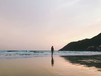 Silhouette man standing on beach against sky during sunset