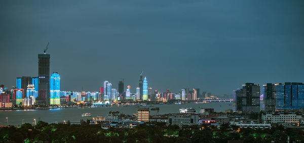 Illuminated buildings in city against sky