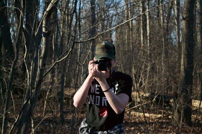 Man standing by tree in forest