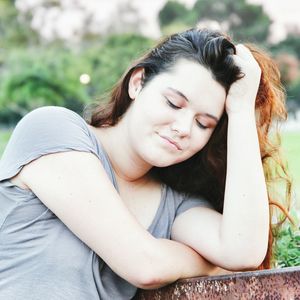 Young woman with hand in hair leaning on railing