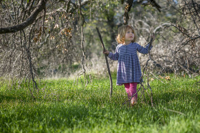 Girl holding sticks while standing on grassy field