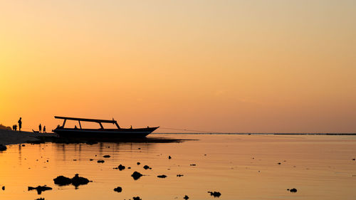 Silhouette boats in sea against orange sky