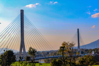 View of suspension bridge against cloudy sky