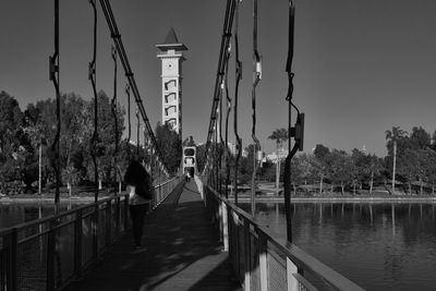 Rear view of woman walking on footbridge