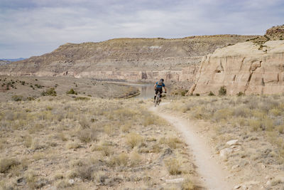 Man riding horse on mountain against sky