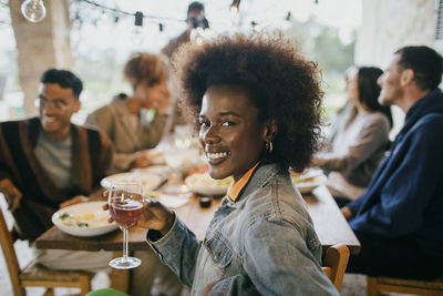 Smiling portrait of young woman with afro hairstyle holding wineglass