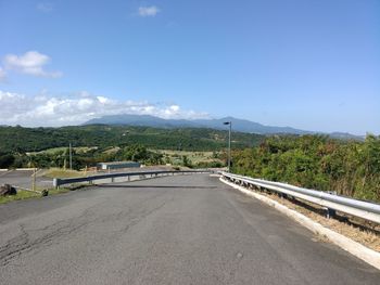 Road leading towards mountain against sky