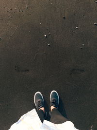 Low section of woman standing on black sand at beach