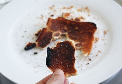 Close-up of hand holding burnt toasted bread