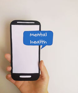 Close-up of hand holding smart phone against white background