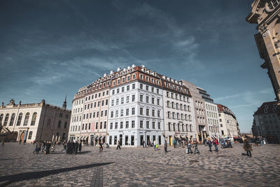 People walking on street against sky in city