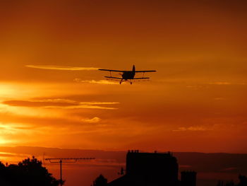 Low angle view of silhouette airplane against sky during sunset