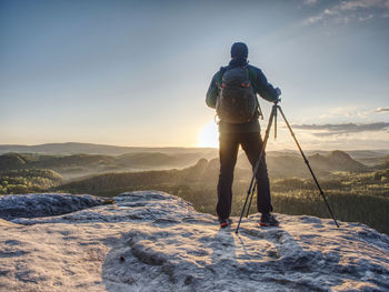 Rear view of man standing on mountain against sky