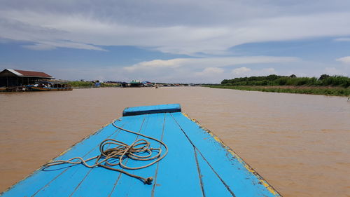 Rope on blue boat sailing in river against sky