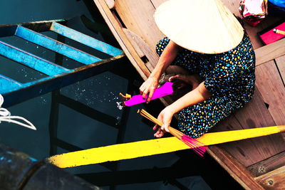 High angle view of woman burning incense sticks in boat