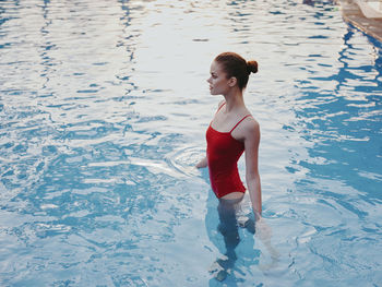 Full length of young woman standing in swimming pool
