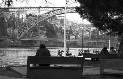 Rear view of men sitting on bridge in city