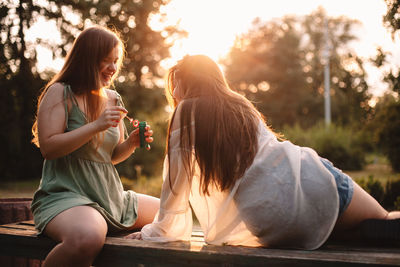 Happy lesbian couple playing with bubbles while relaxing in park