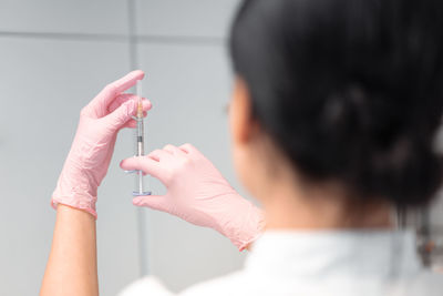Rear view of woman holding thermometer