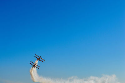 Low angle view of airplane flying against blue sky