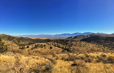 Scenic view of arid landscape against clear blue sky