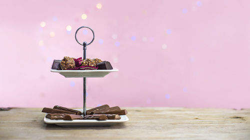Chocolate on container on table in front of pink illuminated wall