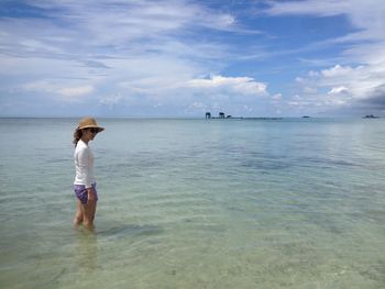 Side view of woman standing in sea against sky