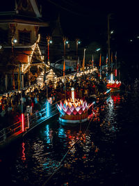 Illuminated boats moored in river at night