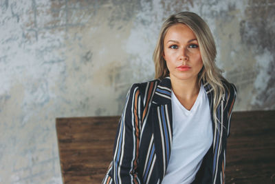 Portrait of woman with long hair against wall