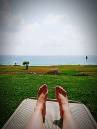 Low section of person relaxing on land against sea