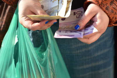 Midsection of woman holding paper currency