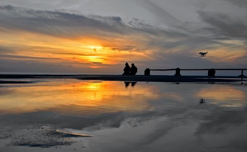 Silhouette woman by sea against sky during sunset