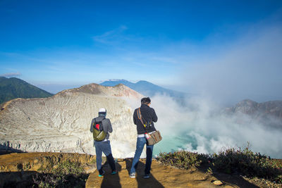 Men standing on mountain against sky