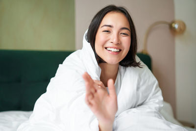 Portrait of young woman sitting on bed at home