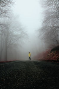 Rear view of man walking on road in foggy weather