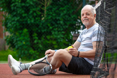 Rear view of man sitting on plant against trees