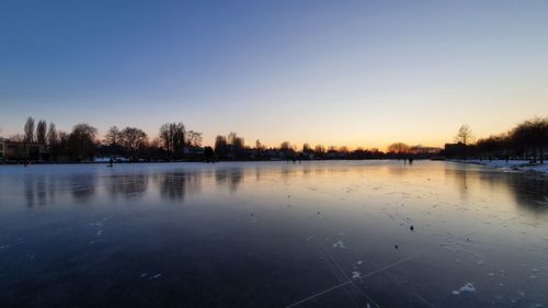 Scenic view of lake against clear sky during sunset