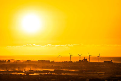 Silhouette cranes against sky during sunset