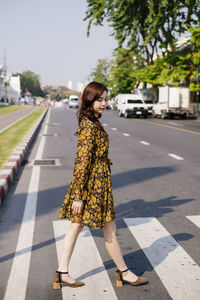 Woman standing on footpath in city