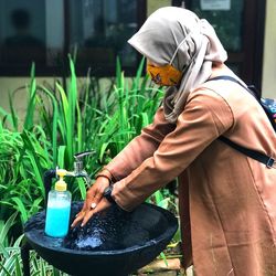 Side view of woman wearing hijab washing hands in sink