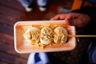 Hand holding dang go japanese snack served on a plate