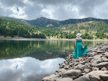 Rear view of woman by lake against sky