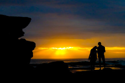 Silhouette man standing on beach against sky during sunset