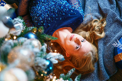 High angle view of caucasian beautiful woman lying on floor near christmas tree