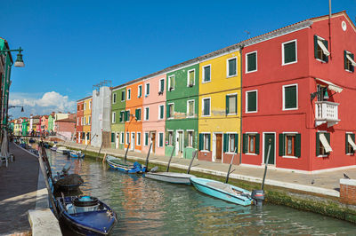 Colorful buildings and boats in front of a canal at burano, a little town full of canals in italy.