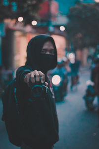 Portrait of man photographing illuminated street at night